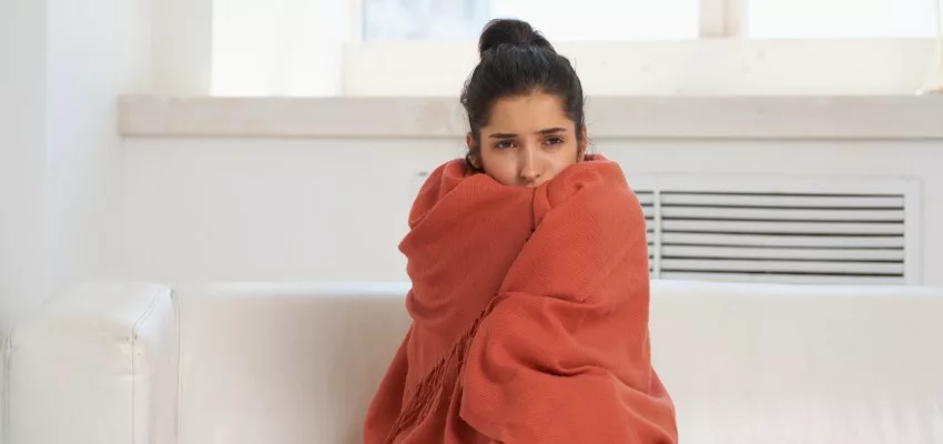 woman warming up with blanket inside home